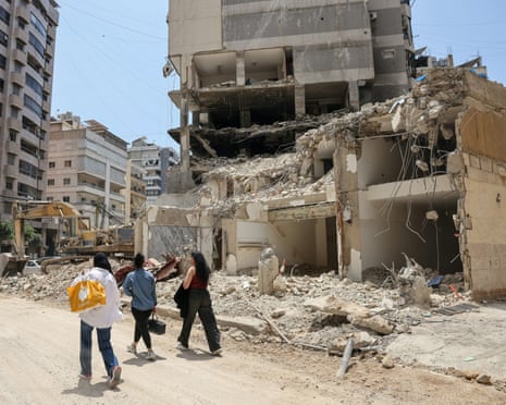 People walk past a destroyed building in Beirut's southern suburbs