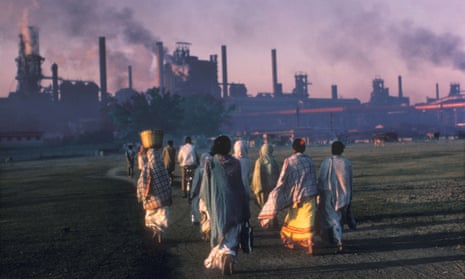 Indian women walk towards a coal plant at sunrise.