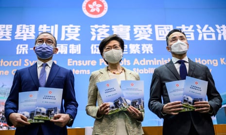 Carrie Lam (centre) held a press conference on the new measures in front of a backdrop that read: ‘Improve Electoral System, Ensure Patriots Administering Hong Kong.’