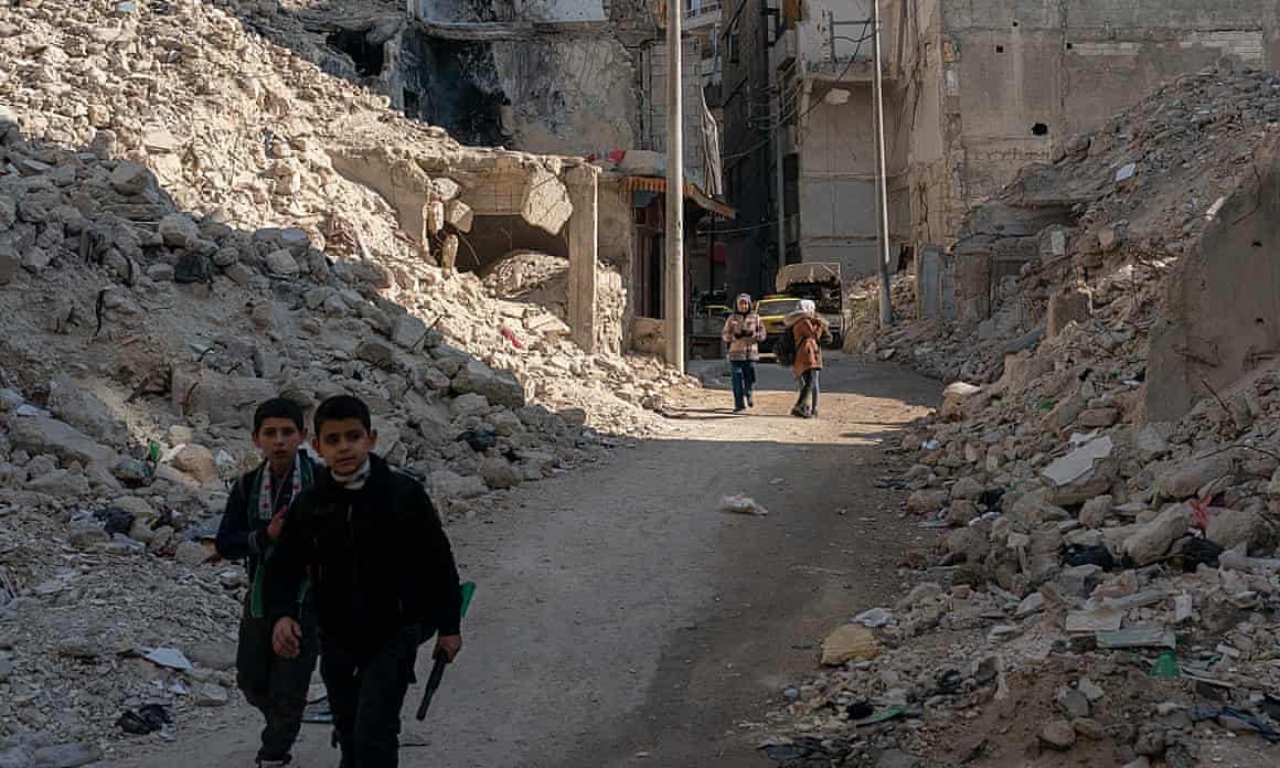 People including children walk through the rubble of Sha’aar neighborhood