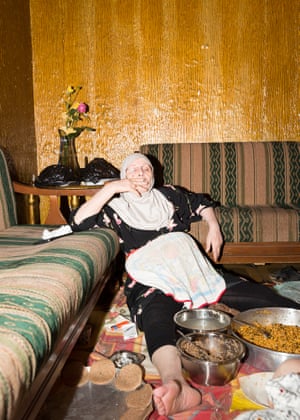 A tired mother lays back in her living room holding a cigarette.