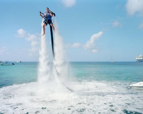 PAOLO WOODS & GABRIELE GALIMBERTI's series
THE HEAVENS, ANNUAL REPORT on shoe at Arles Photo Festival 2015
An employee of "Jetpack Cayman" demonstrates this new watersport, now available on the island. A 2000cc motor pumps water up through the Jetpack, propelling the client out of the sea (359 USD for a 30-minute session). Mike Thalasinos, the owner of the company, remarks, The Jetpack is zero gravity, the Cayman are zero taxes, we are in the right place! Grand Cayman.