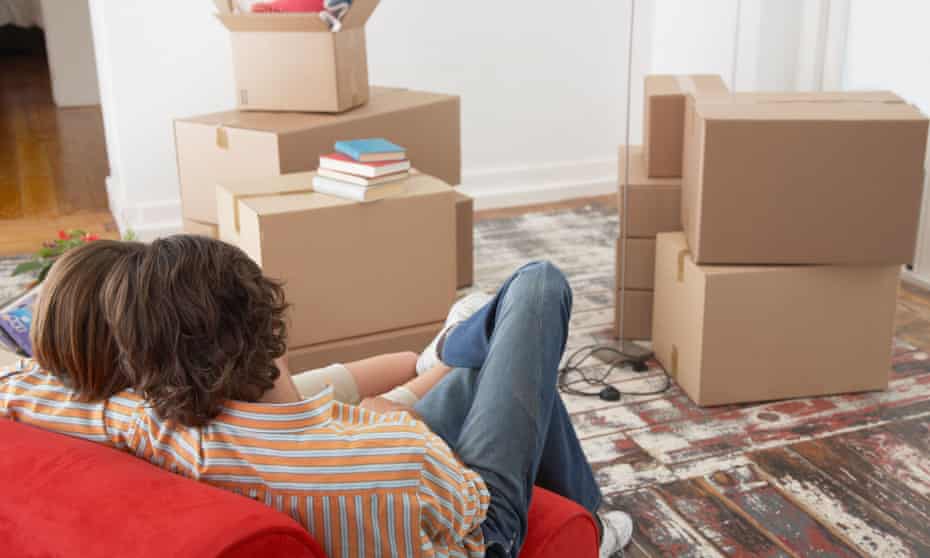 Rear view of couple on red chair in house with cardboard boxes