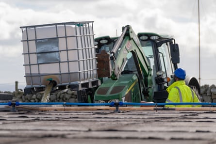 Workers use a tractor to top up a water tank.