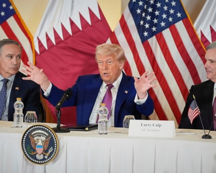 Trump with arms outstretched seated between Kelly Ortberg, president and CEO of Boeing, left, and Larry Culp, CEO of GE Aerospace, with flags behind
