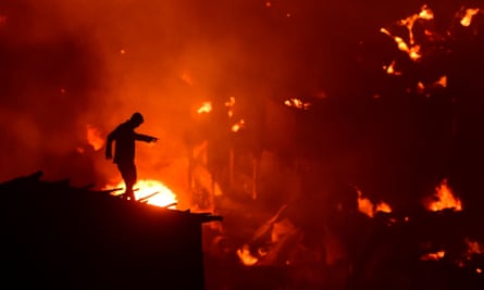 A Bangladeshi man tries to extinguish flames as a fire ravages a slum in Dhaka.
