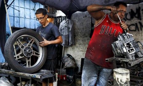 Motorcycle mechanics work at a makeshift repair shop on the street in Caracas.