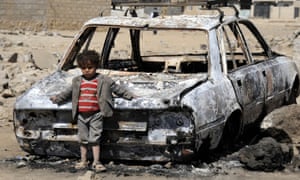 A child leans against a burned-out car following airstrikes by the Saudi-led coalition in Sana’a, the capital of Yemen