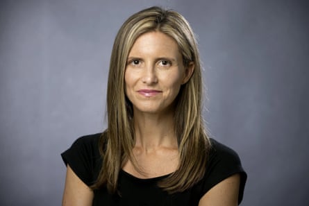 Sara Novak, a journalist, smiles slightly in a black top against a grey backdrop