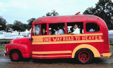 Robert Duvall sitting at the front of an old red bus with the words 'One way road to heaven' painted on its side
