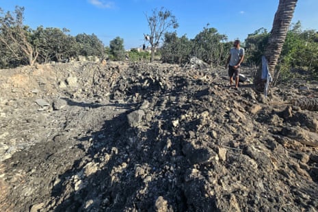 A man stands by a crater left by an overnight Israeli airstrike.