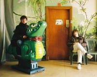 Ben Sadler sitting on a plastic chair, and Josh Law on a crocodile kiddie ride