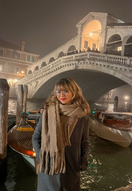 Woman poses with bridge over water behind her