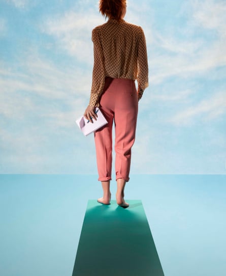 A model standing on a diving board looking at the horizon, and holding a pad and pen