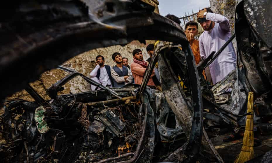 Relatives and neighbors of the Ahmadi family gathered around the incinerated husk of a vehicle targeted and hit by an American drone strike, on 30 August. 