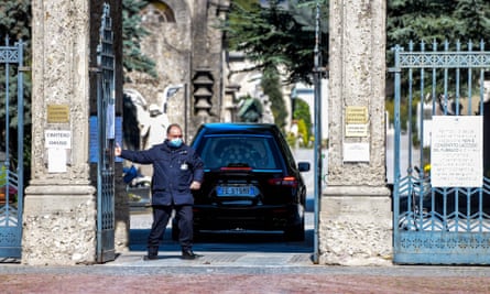 A cemetery employee closes the gates behind a hearse at the Monumental cemetery of Bergamo