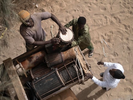 Seen from above, men off-load a variety of drums from a cart at the venue for the showing of Io Capitano in Pikine, Dakar.