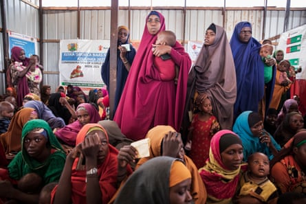 Somalian women and small children wait in a temporary shelter.