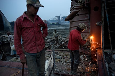 Laborers on Chittagong beach use blowtorches to disassemble parts of a mega freighter.