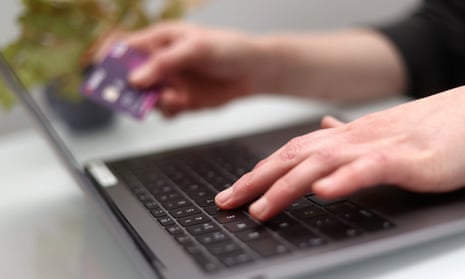 a woman using a laptop as she holds a bank card.