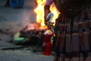 La Paz, Bolivia. A coca farmer holds a container of vinegar to counteract the effects of teargas and a face mask after clashes with police