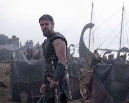 Matt Damon wearing period dress, in front of a boat and men gathered on the shore