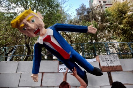 People in Mexico City protest against Donald Trump’s inauguration next to a fake wall with a dummy representing him.