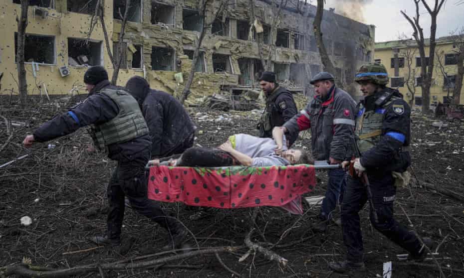 Ukrainian emergency workers and volunteers carry an injured pregnant woman from a maternity hospital that was damaged by shelling in Mariupol