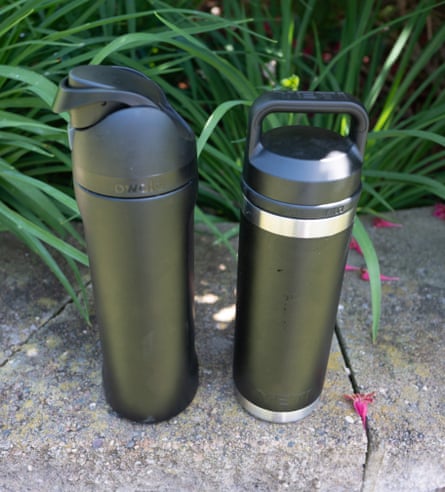 two water bottles next to each other outside on stone wall by plants