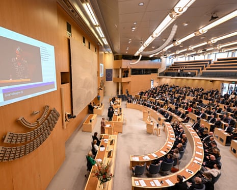 MPs fill the Swedish Riksdag chamber during the prime ministerial vote, screen showing a speaker