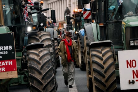 Towler walking down a road towards the camera between rows of parked tractors