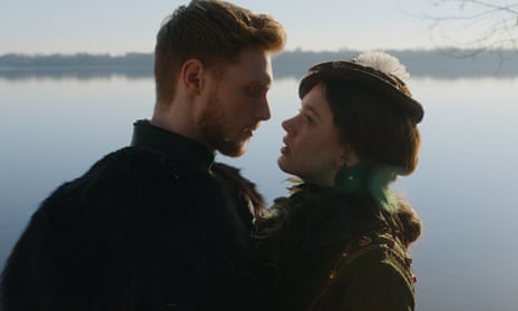 Close-up of Amy James-Kelly and Max Parker seen in profile in front of a lake