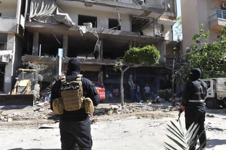 Members of security forces gather near a heavily damaged apartment building.