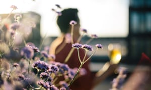 Blurred shot of Jonny Wong holding glass of Stella Artois with flowers in focus in foreground