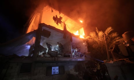 People use the lights on their phones to search for people in a smouldering building after an Israeli airstrike in Rafah in the southern Gaza Strip.