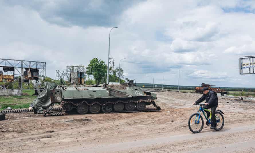 A man rides a bicycle in front of a damaging BMP on the outskirts of Kharkiv, Ukraine.