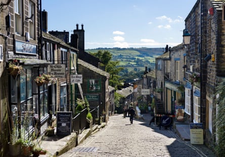 People walk down Main Street in Haworth, West Yorkshire, on a sunny day.