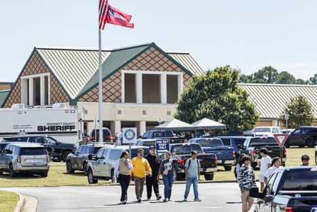 A group of teenagers walks away from a building and a flagpole.