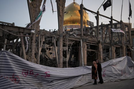 Pedestrians look at a destroyed building within the Grand Hosseiniyeh complex in Zanjan in Iran with a golden mosque visible in the background