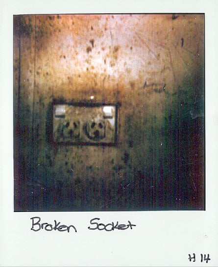 A Polaroid photo of a double electrical outlet on a wall. The image is tinted flown and the wall is flecked with marks