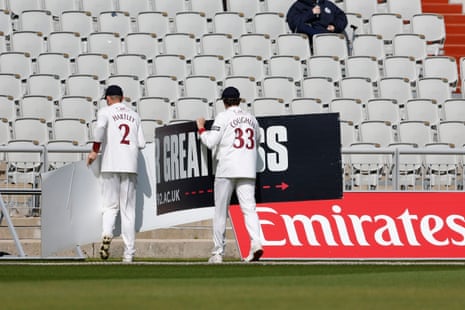 Lancashire pair Tom Hartley and Paul Coughlin remove a sign blown on to the field at Old Trafford