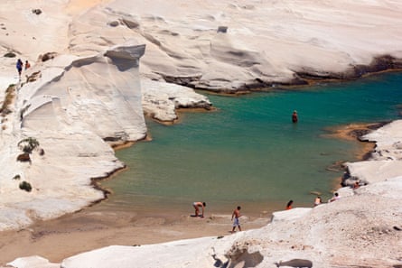 People swimming in Sarakiniko beach, known as the ‘moon beach’.