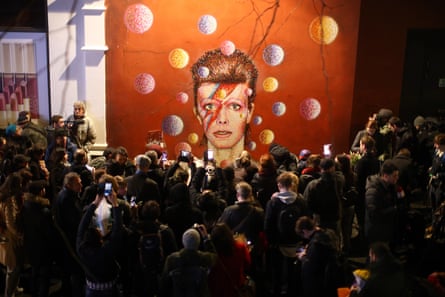 Members of the media and public gather by a mural of David Bowie in Brixton on 11 January