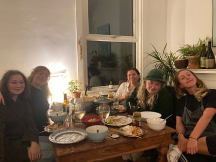 Five young people sat around a table with food