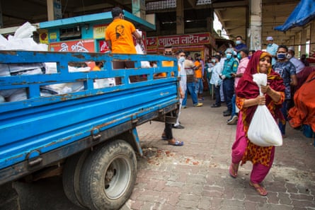 A woman walks away from a food-relief truck with a sack of produce