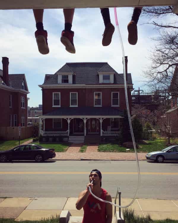 A college student drinking through a long beer bong.
