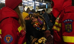 A Romanian emergency rescue service SMURD volunteers chat near a group of people who fled the conflict, and arrived in Romania, on March 1, 2022 in Isaccea, Romania.