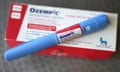 A blue Ozempic injector sits on a red and white  Ozempic-branded box