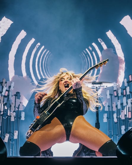 woman in black bodysuit plays guitar on stage