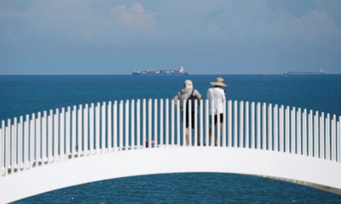 Tourists stand facing container ships in the waters off the 68-nautical-mile scenic spot in Pingtan island, one of mainland China’s closest points to the island of Taiwan.